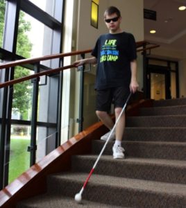 Photo of a student using a white cane while walking down stairs